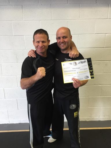 Two men in sports attire, one holding a certificate, both smiling and celebrating.